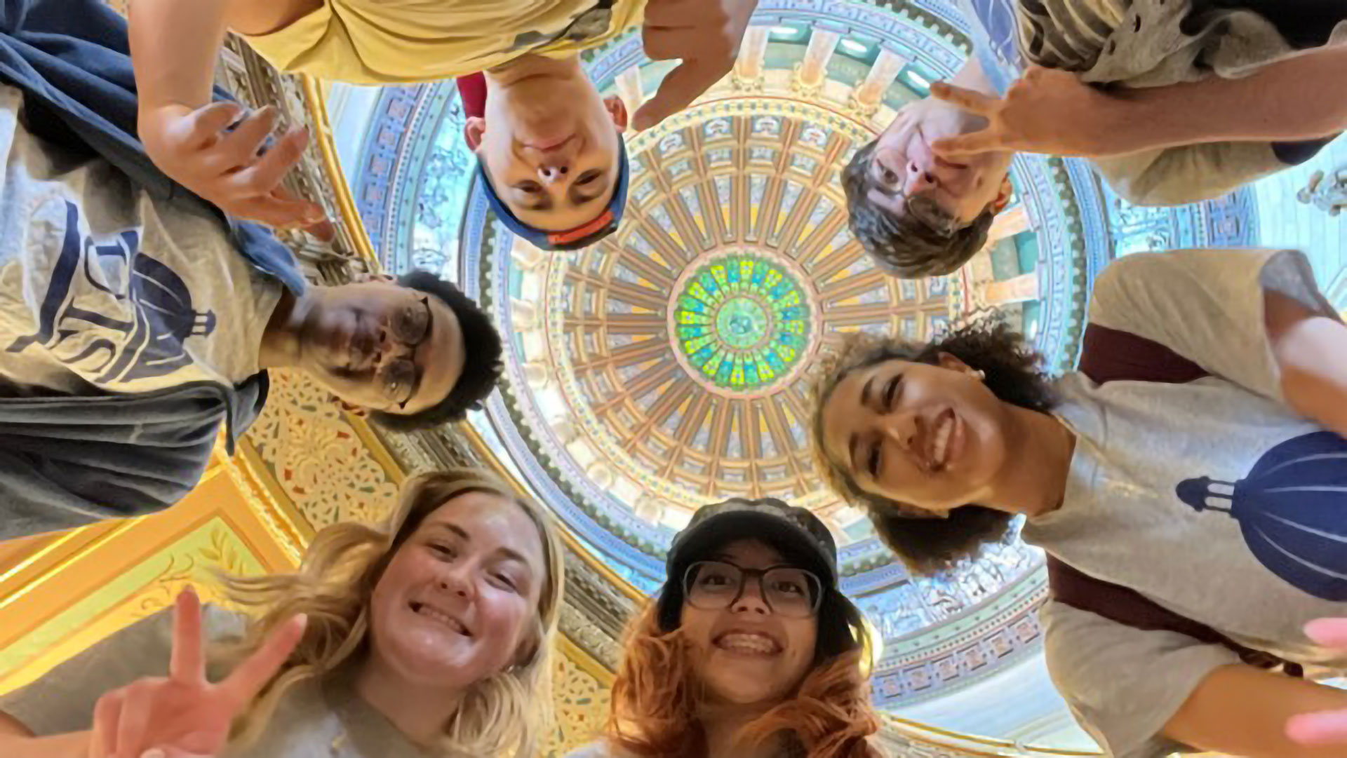 students in a circle surrounding the camera in the Illinois State Capitol Building
