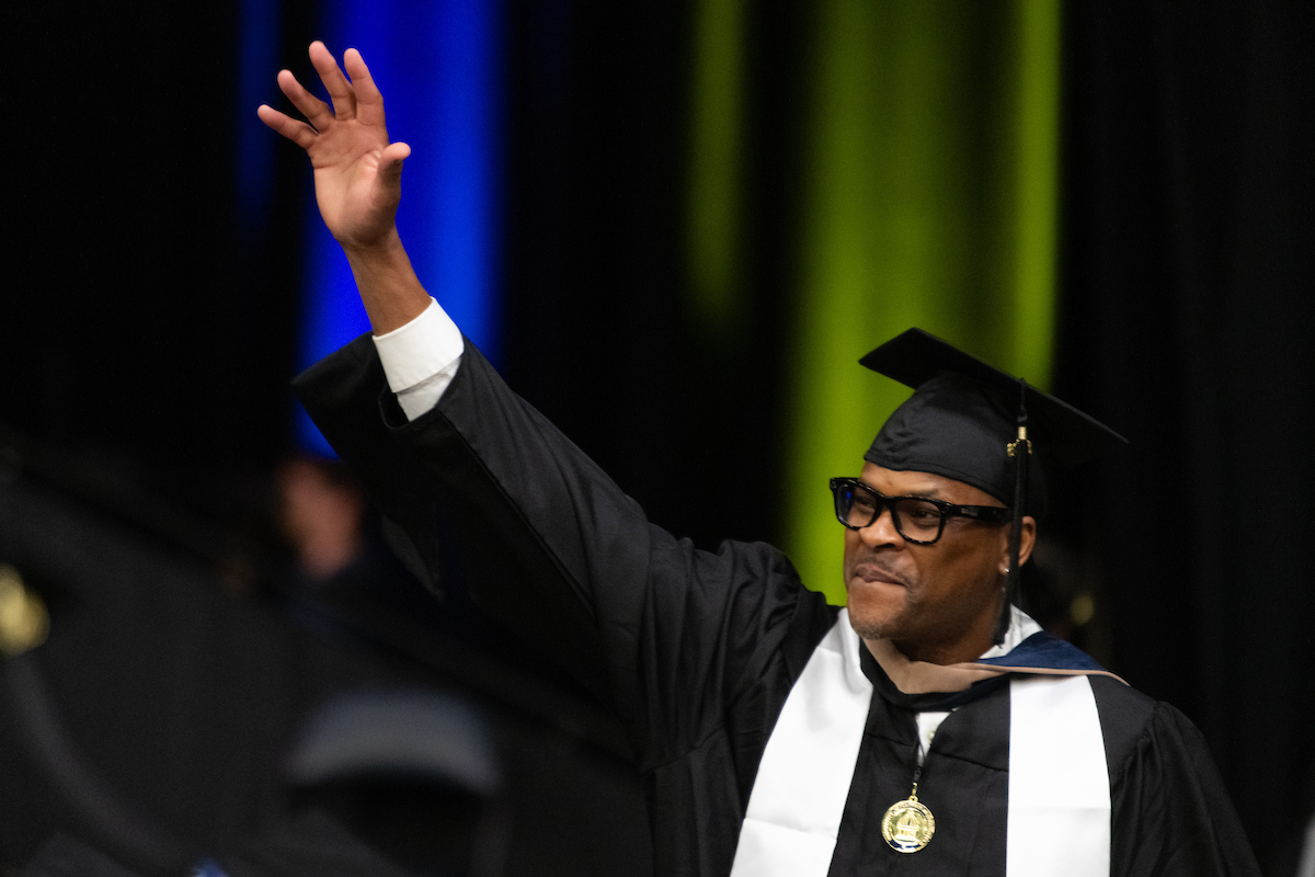 graduate waving at crowd with medallion around neck
