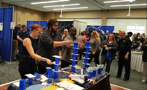 Three people playing a game that involves paper layered in between plastic cups.