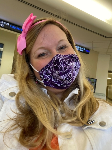 A woman with a pink bow in her hair wearing a face mask. 