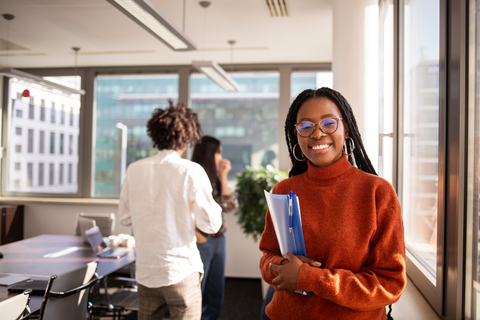 Smiling student holding folders in a modern campus study area