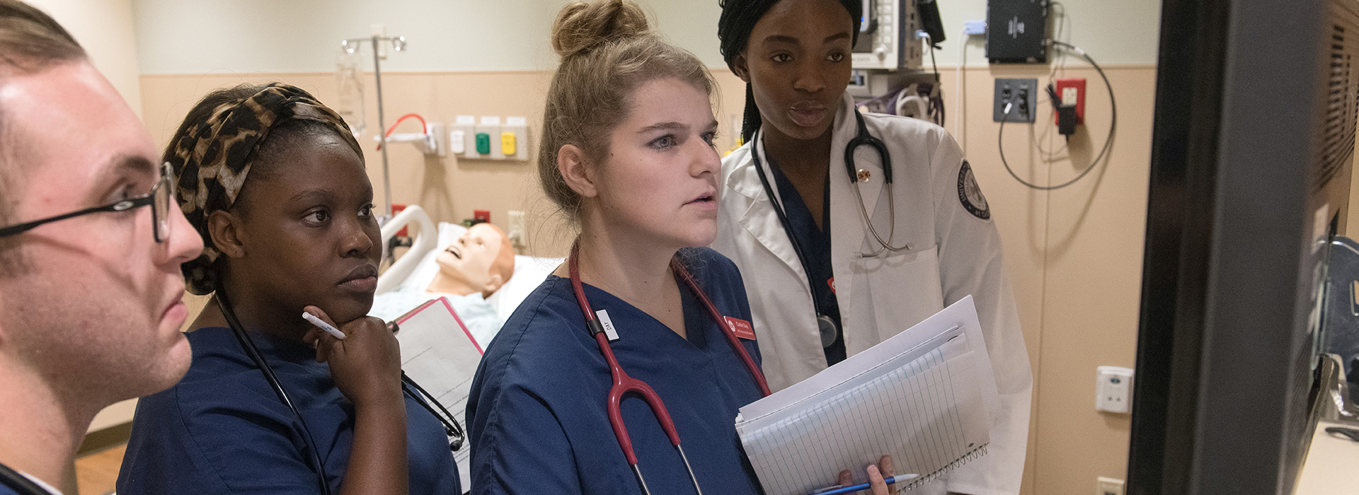 Nursing students in simulator looking at a computer screen