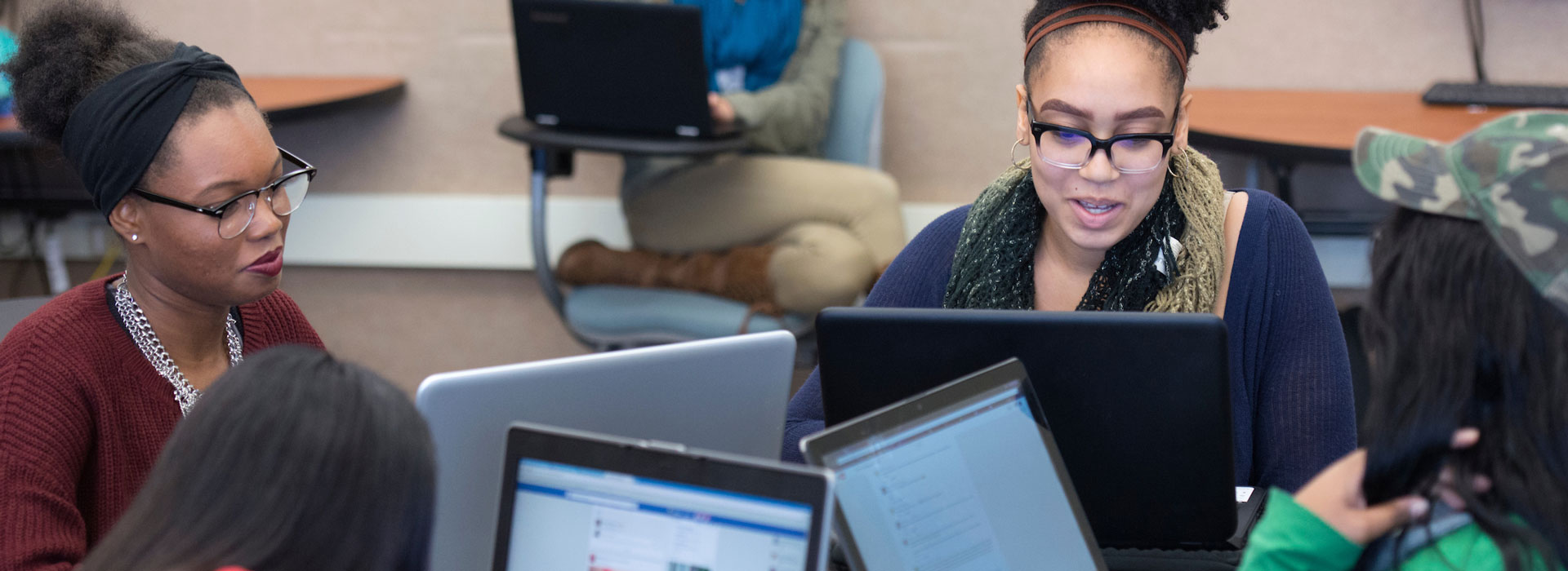 Group of students collaborating with open laptop computers