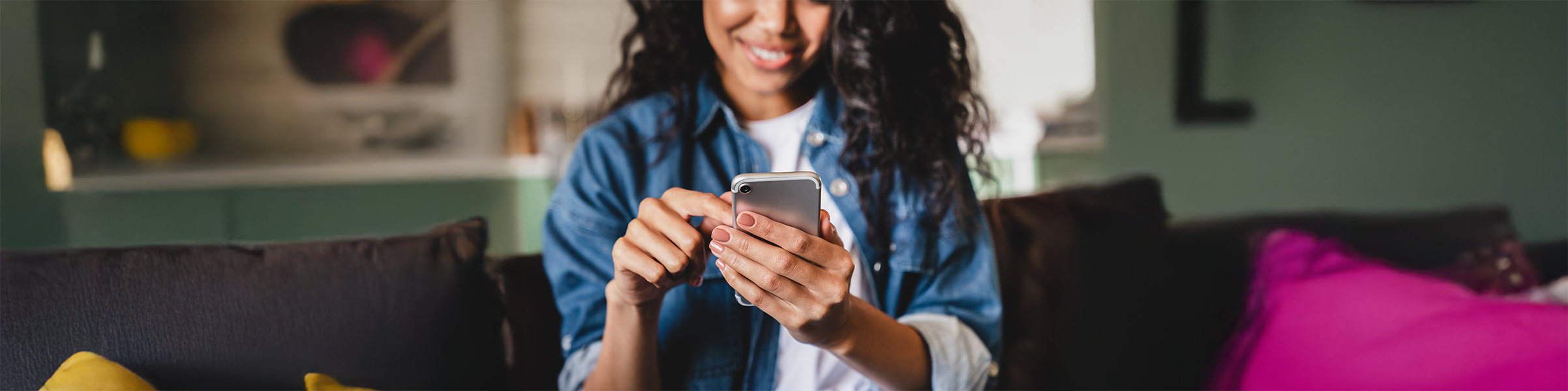 Woman smiling and scrolling on her phone with gradient background.