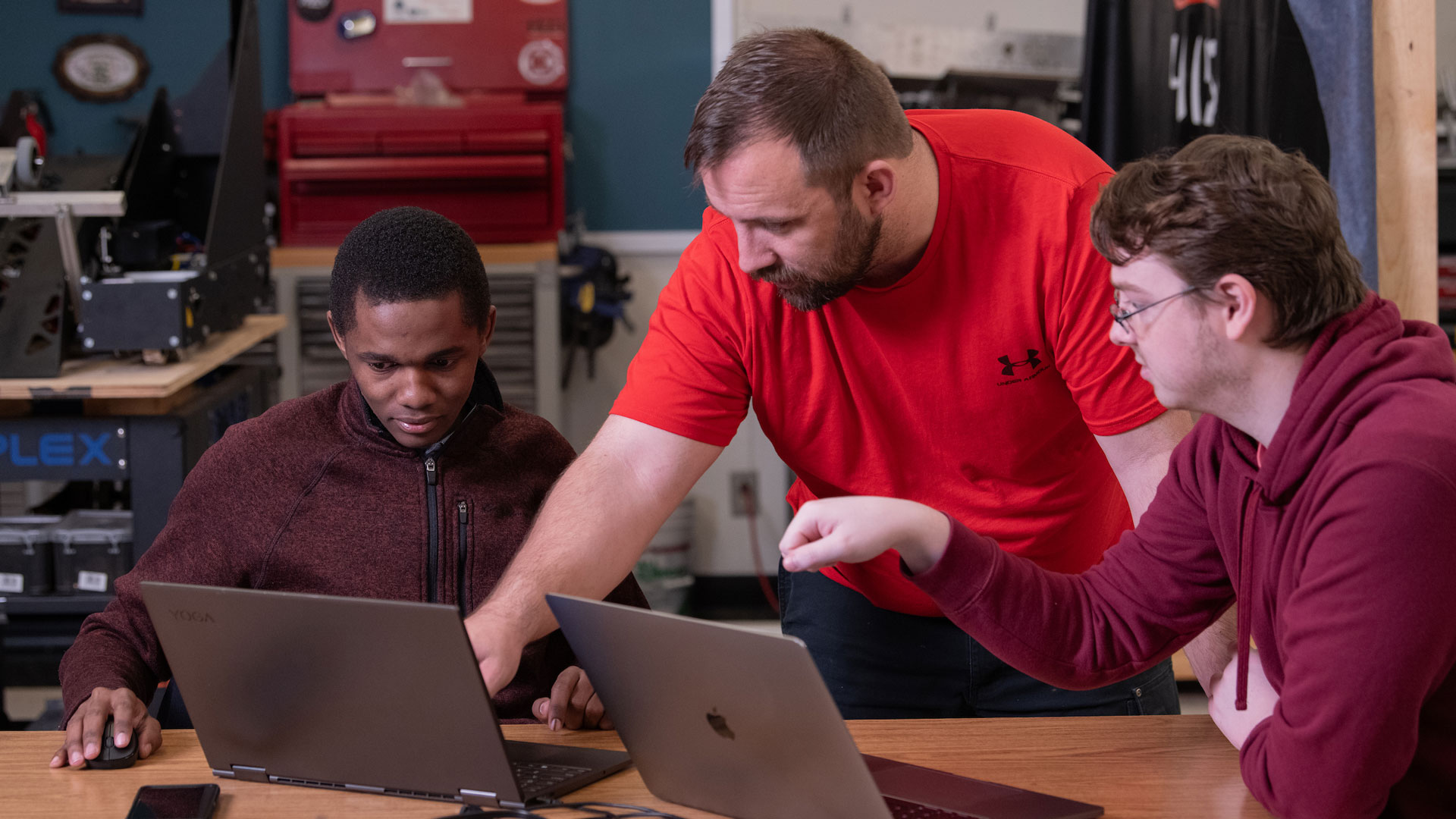 a professor explaining something on a computer to two students