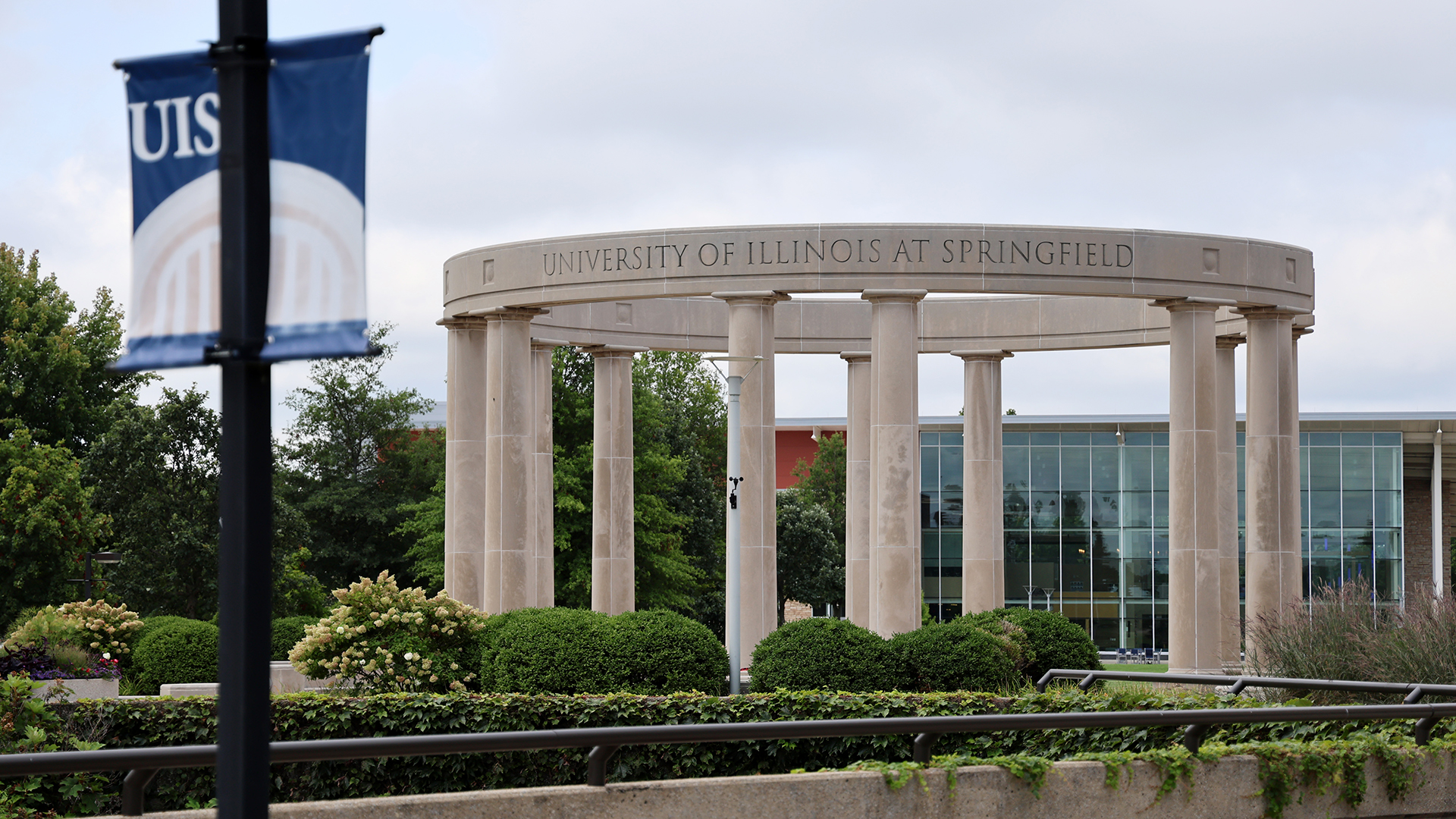 Campus Colonnade; nearby, a "UIS" banner and building in background.