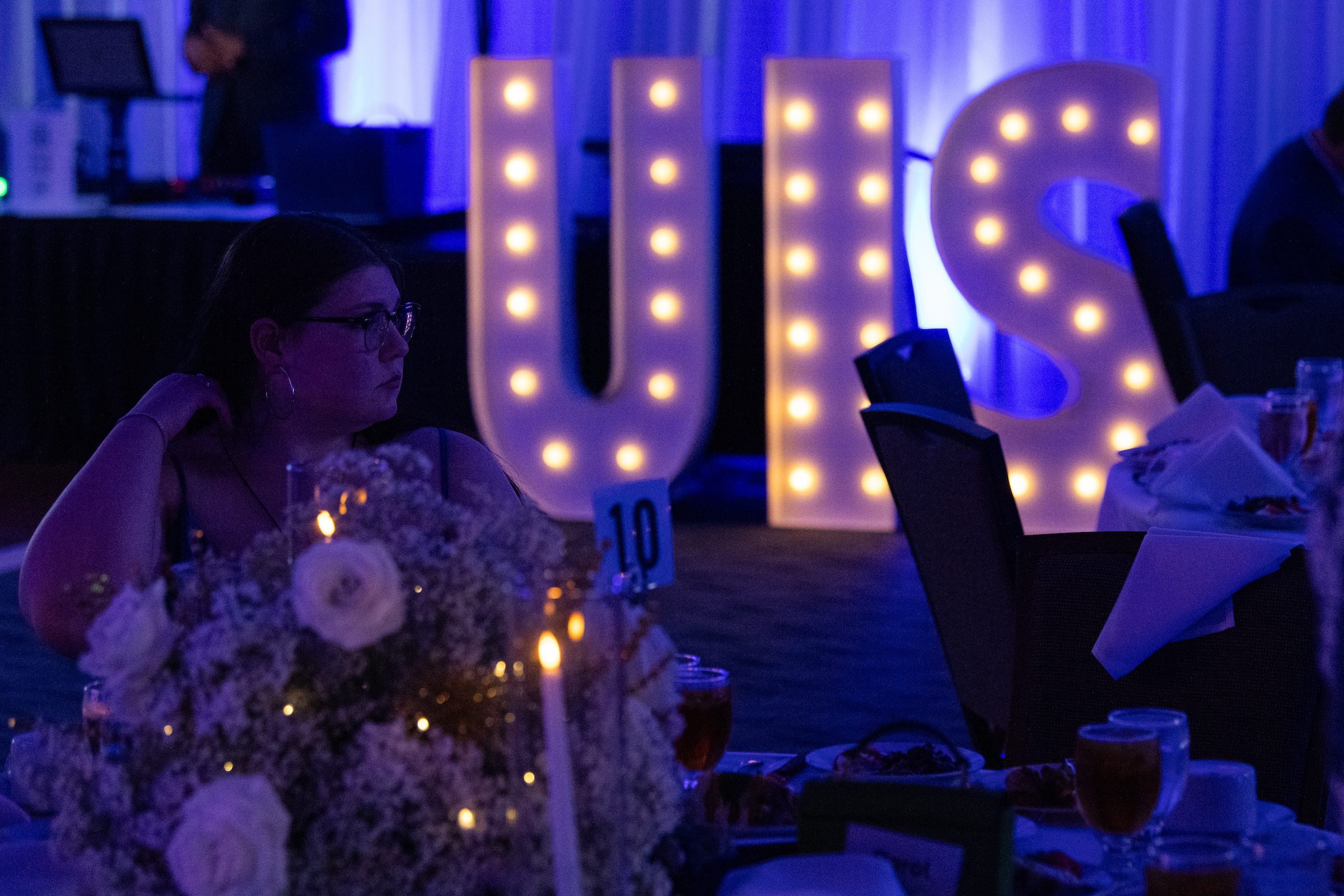 Glowing marquee letters "UIS" in a dimly lit event setting.