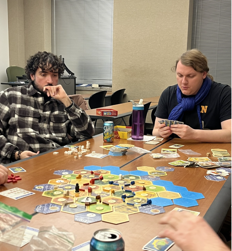 Two people sitting at at able and playing a board game.