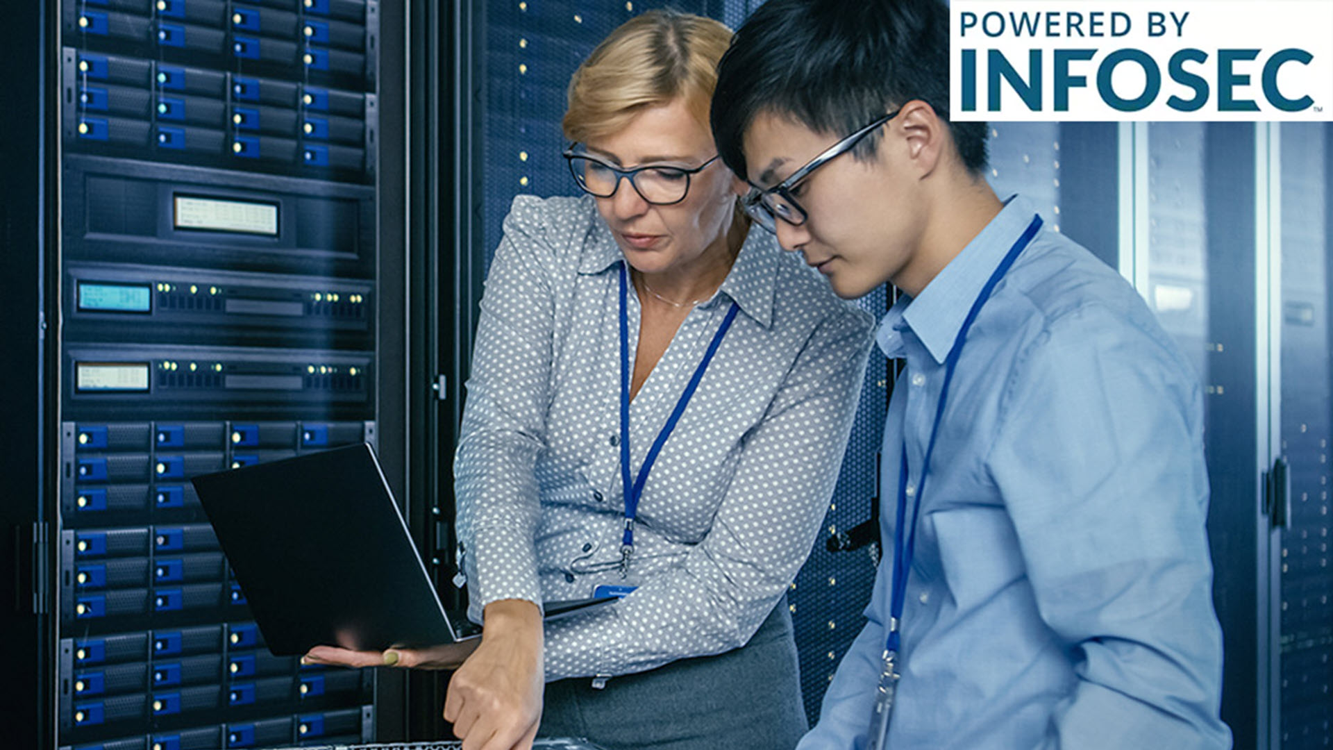 Two people working on a laptop in a server room, focused and engaged.