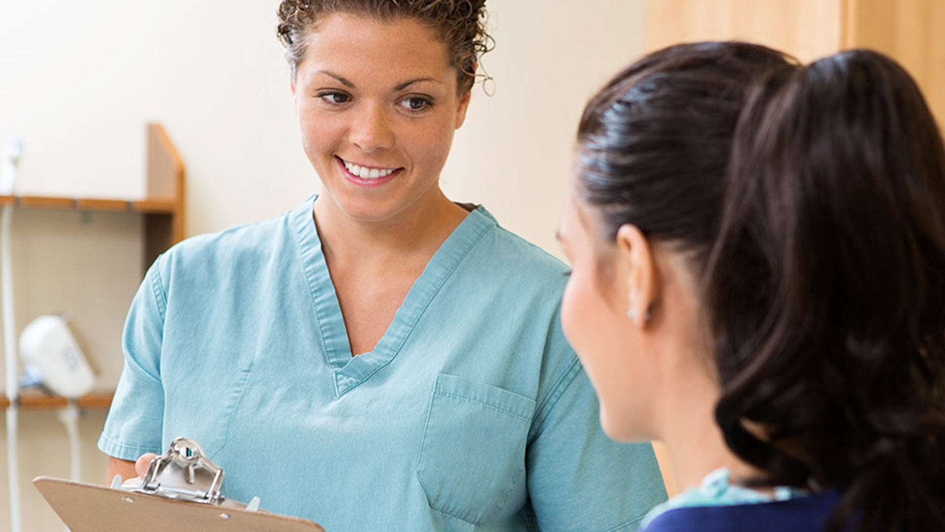 Nurse smiling at patient while holding a clipboard.