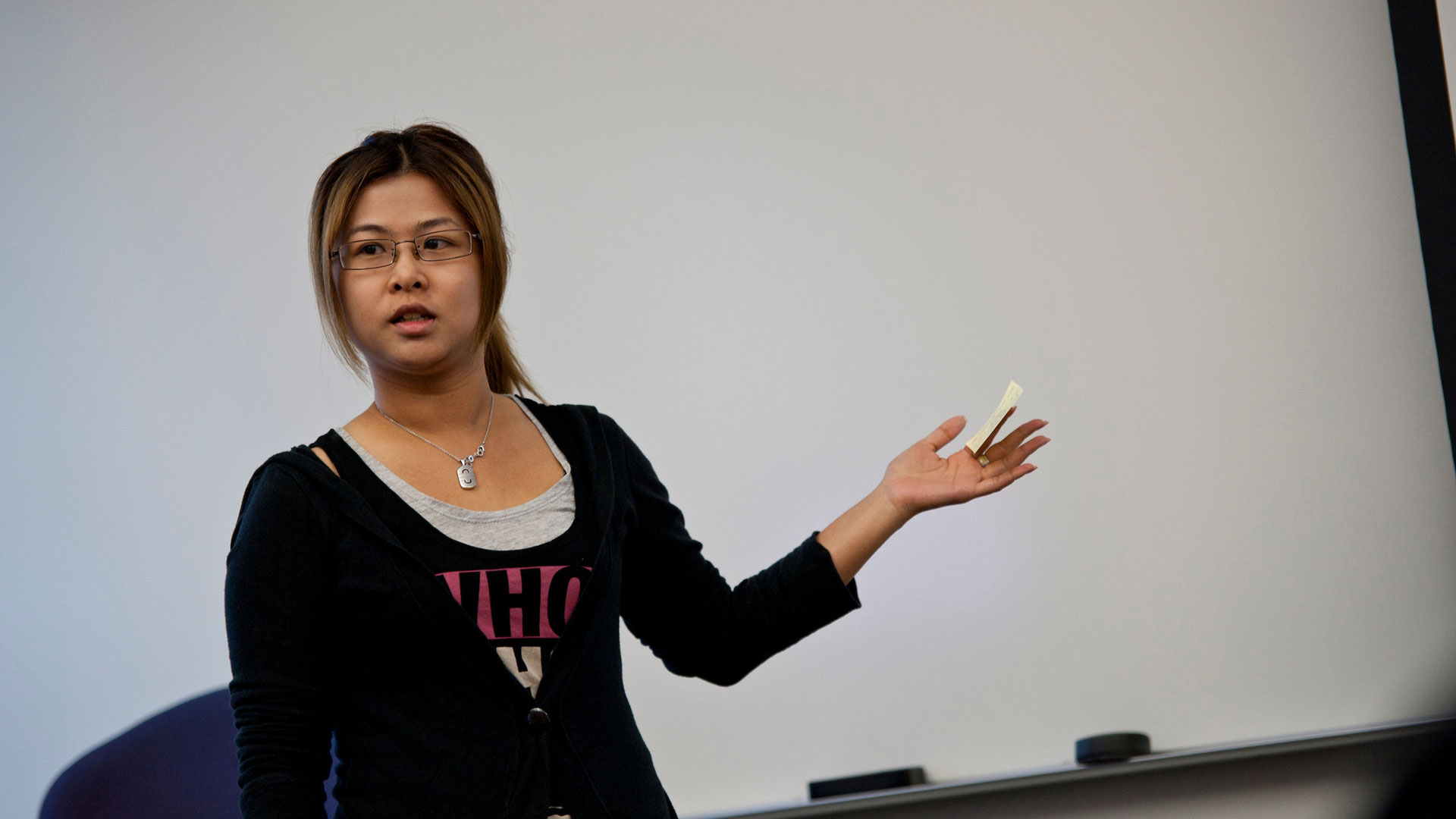 a female teacher speaking to the class in front of a white board