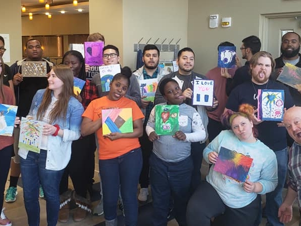 A group of people posing with their paintings.