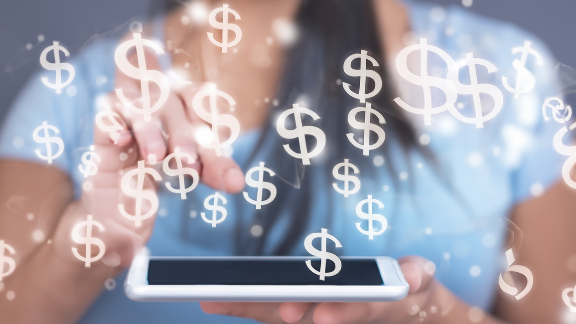 A person using a tablet with dollar signs appearing