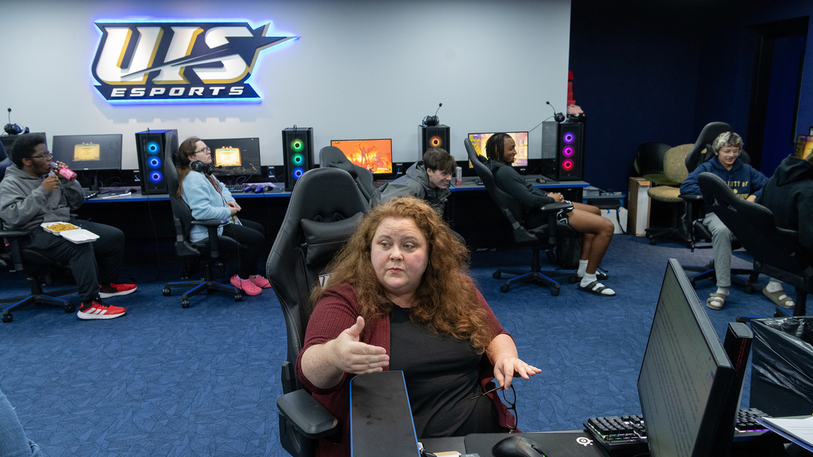 An instructor speaks to students sitting in gaming chairs in the Esports Arena.