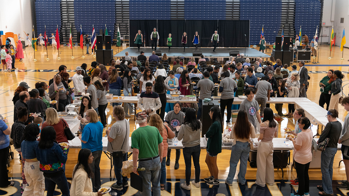 People line up for food as performances take place on stage.