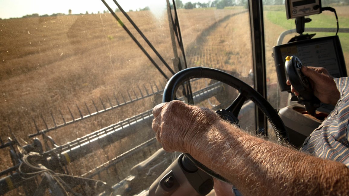 close up of hands on the wheel of a combine