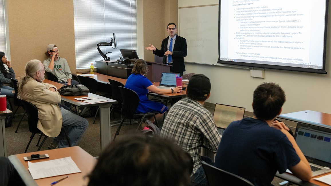 Students sitting at desks in a classroom as a professor teaches. 