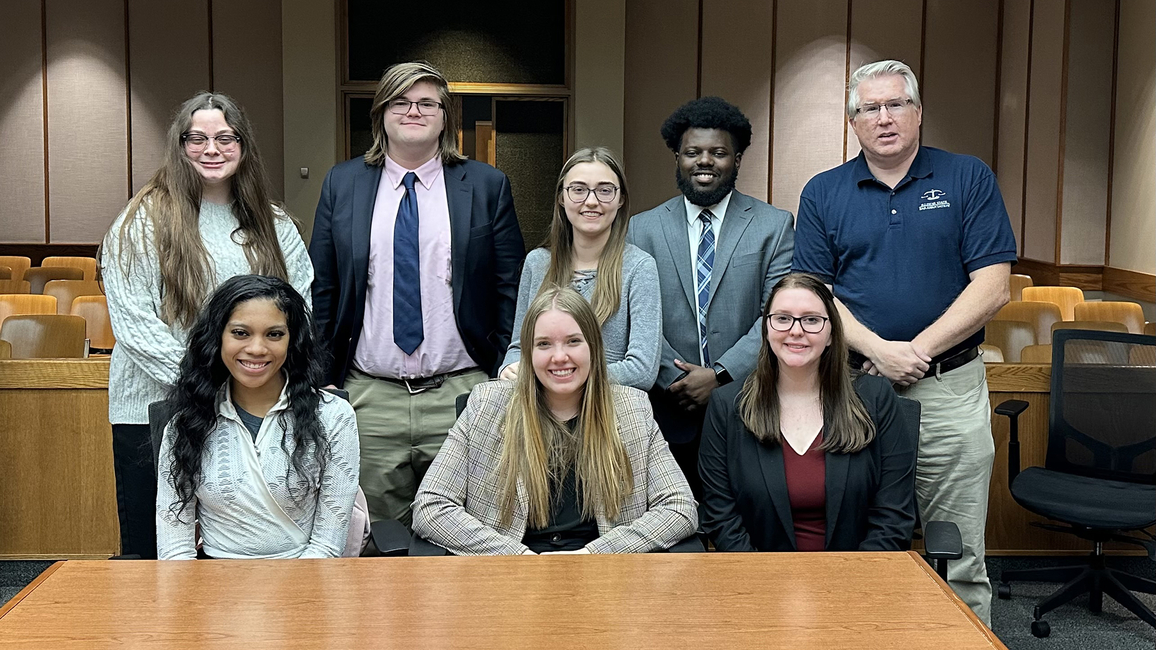 A group of Mock Trial students pose in a courtroom.