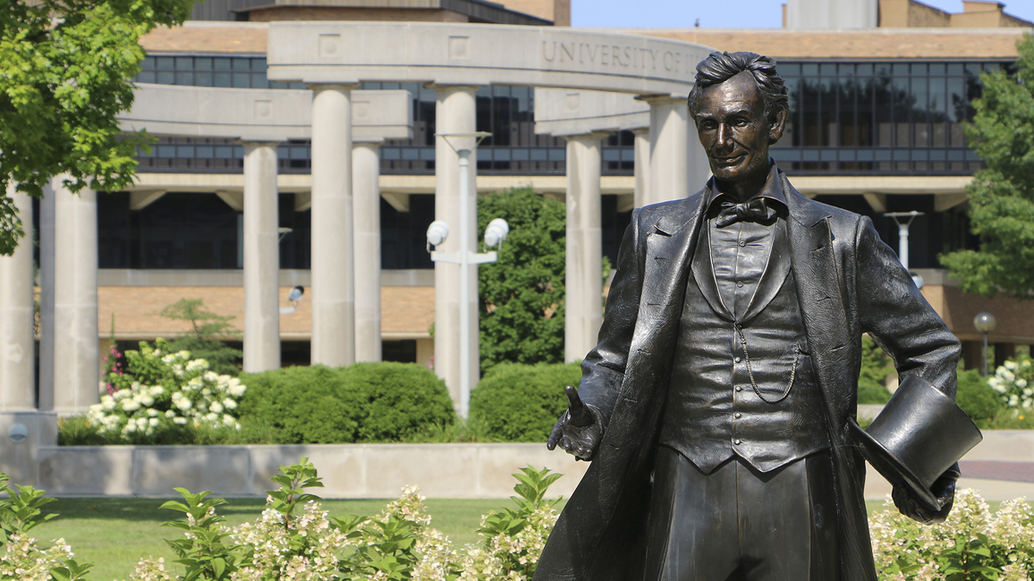 Statue of Abraham Lincoln with the UIS colonnade in the background.