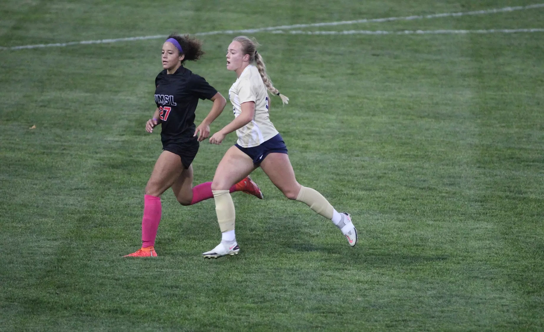 Carolyne Mathenia running on the pitch with an opponent