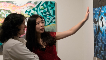 Two women discussing a painting at the UIS Visual Arts Gallery