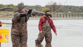 people standing in the water with camouflage overalls