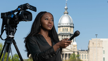 a student interviewing someone offscreen with a microphone and camera