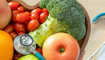 a stethoscope laying on top of a heart shaped bowl full of fruits and vegetables