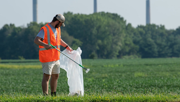 a volunteer picking up trash in a field