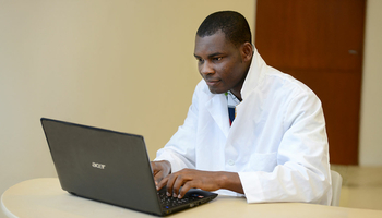 student in lab coat at computer