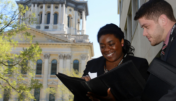 two lawmaker students looking over paperwork on the steps of the state capitol