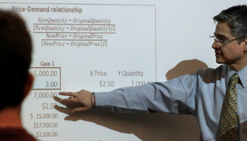 accounting professor pointing to formulas on the whiteboard