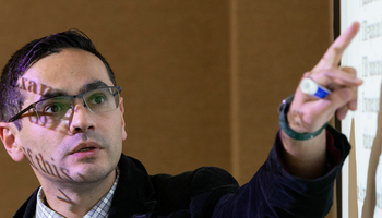 a professor teaching and pointing at the white board at a sentence