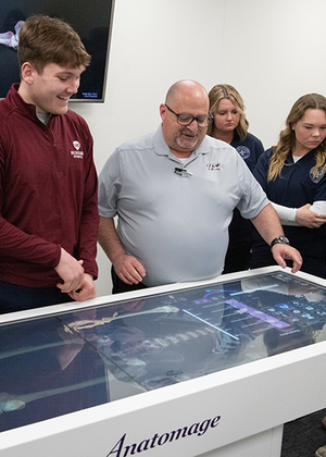 Four people stand in front of a antomage table