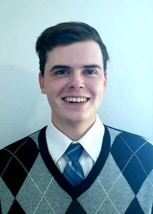 Profile photo of Connor Krater, a smiling young white man wearing a blue and gray argyle sweater.