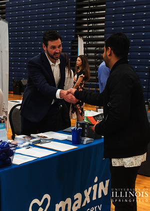 An employer meeting a student at a job fair.