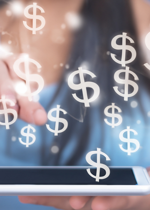 A person using a tablet with dollar signs appearing