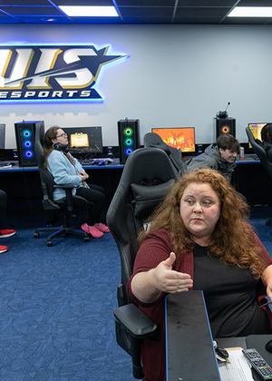 An instructor speaks to students sitting in gaming chairs in the Esports Arena.