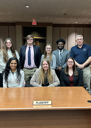 A group of Mock Trial students pose in a courtroom.