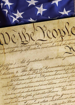 Close-up of the United States Constitution with the words “We the People” visible, placed over an American flag background.
