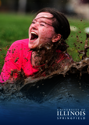 A girl smiles as she plunges into the mud.