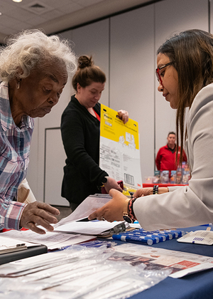 People interacting at a table with documents and supplies.