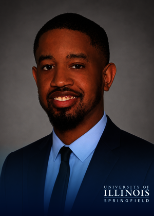 Smiling man in a suit and tie, University of Illinois Springfield logo.