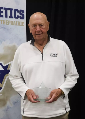 Phil Coady stands on stage with Prairie Star Pillar Award