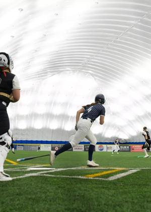 A photo of Bailey Masching and others running the bases at softball tournament in Scheels Sports Dome
