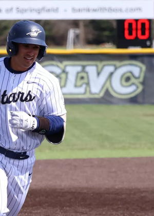 Tommy Atkinson rounding third  in white UIS baseball uniform