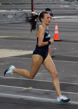 Madelyn Miller-Ross running indoor track in blue UIS uniform