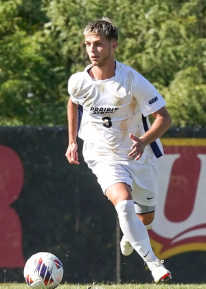 Adam Knaze playing soccer in white UIS uniform