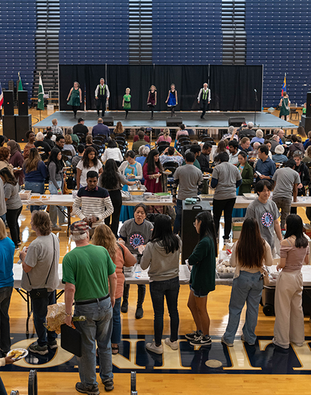 People line up for food as performances take place on stage.