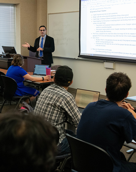 Students sitting at desks in a classroom as a professor teaches. 